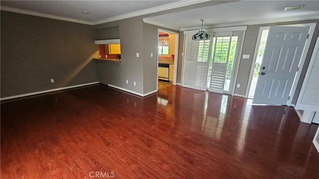 a view of an empty room with a window and wooden floor