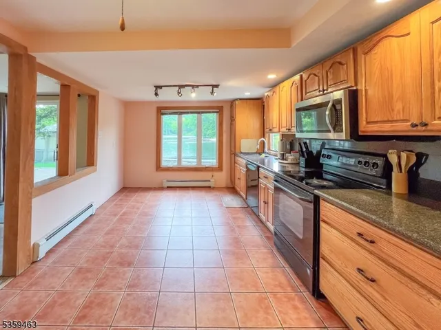 a large kitchen with stainless steel appliances granite countertop a stove a sink and a microwave