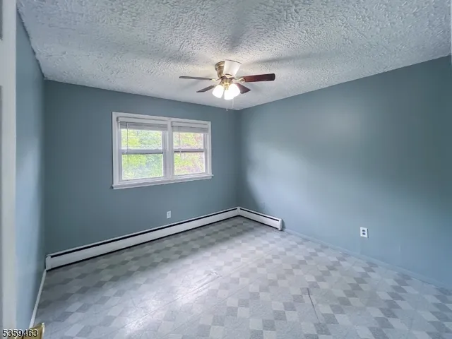 an empty room with windows and fan