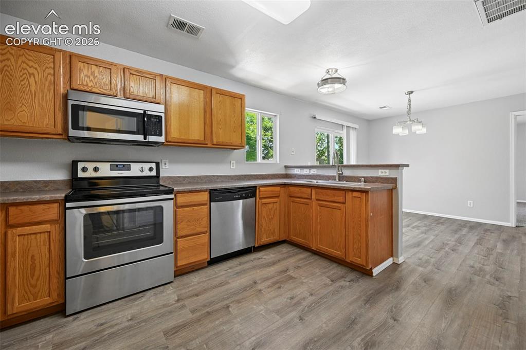 431 Kitfield View Colorado Springs, CO 80916 - Photo 15 of 27 a kitchen with stainless steel appliances granite countertop wooden cabinets a sink a stove a refrigerator and microwave with wooden floor