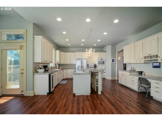 a kitchen with a wooden floor and a view of living room