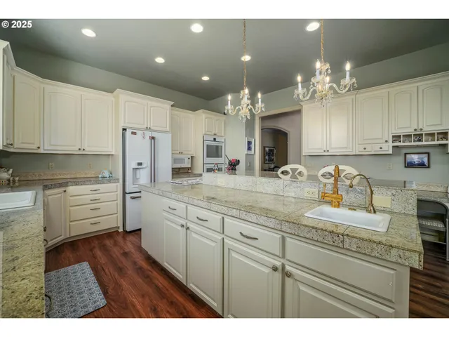 a kitchen with kitchen island granite countertop a sink cabinets and stainless steel appliances