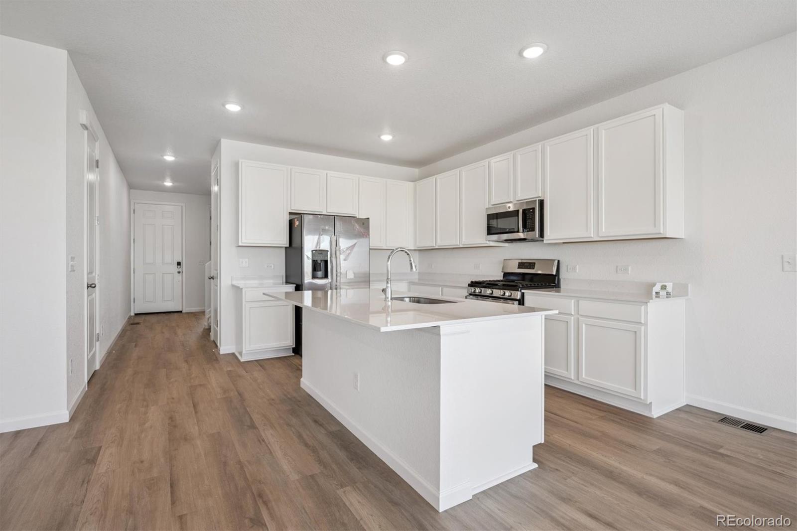 45929 Gentry Avenue Bennett, CO 80102 - Photo 7 of 24 a kitchen with white cabinets and stainless steel appliances