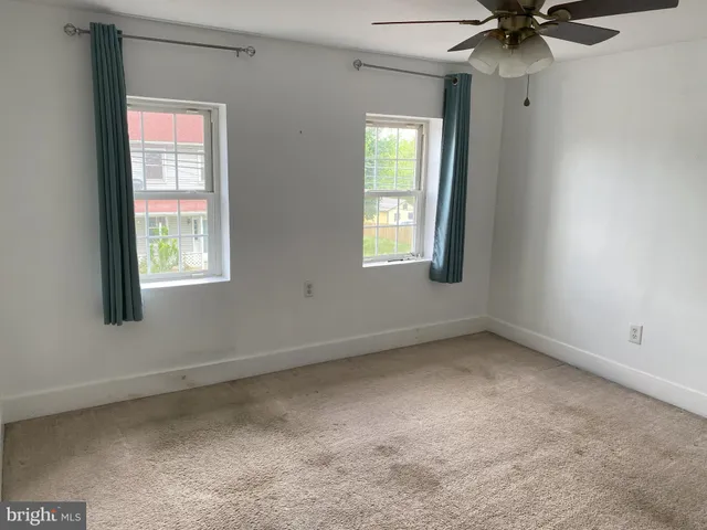 an empty room with a window and a fan