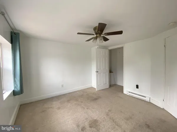 an empty room with a window and a ceiling fan