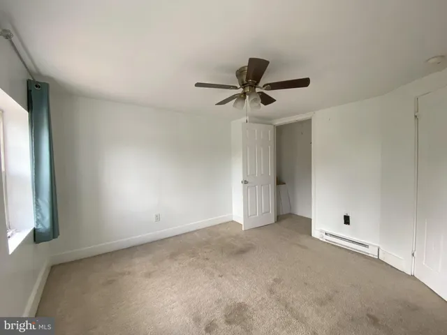 an empty room with a window and a ceiling fan