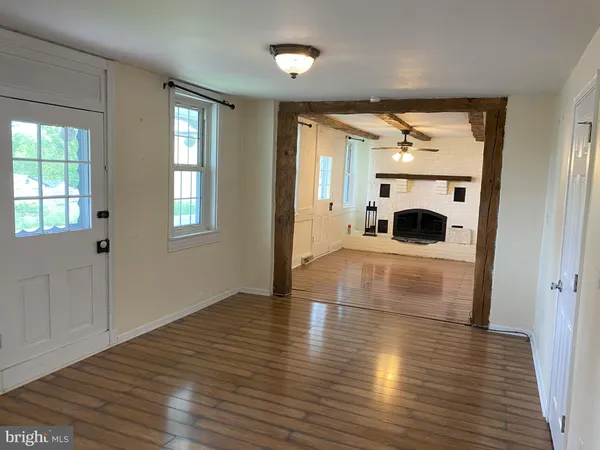 an empty room with wooden floor a fireplace and windows