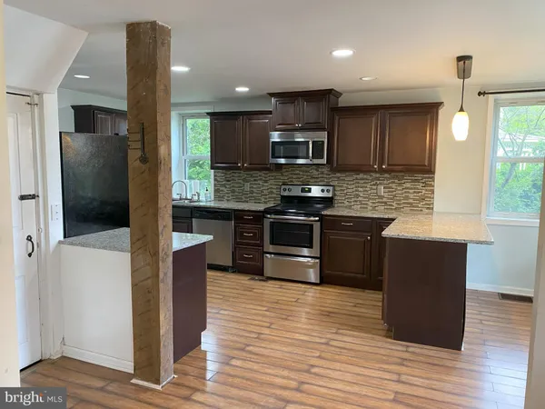 a kitchen with stainless steel appliances kitchen island granite countertop a stove a refrigerator and a sink