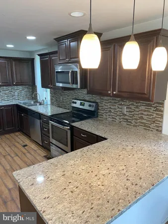 a kitchen with stainless steel appliances granite countertop wooden cabinets a stove a sink and a dishwasher