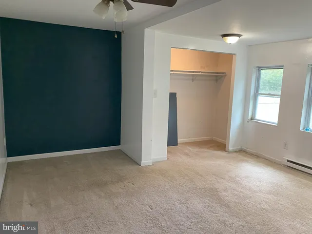 an empty room with windows and fan