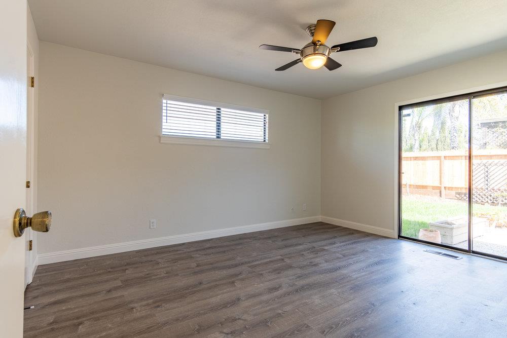 1220 Heather Glen Circle Hollister, CA 95023 - Photo 23 of 41 an empty room with wooden floor and windows with ceiling fan