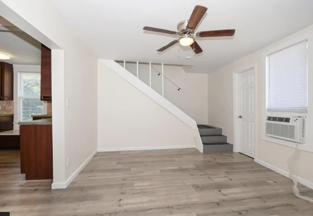 a view of a livingroom with wooden floor stairs and a ceiling fan