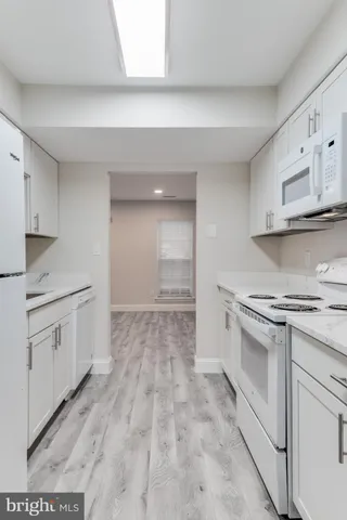 a kitchen with granite countertop white cabinets and white appliances