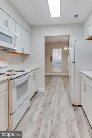 a kitchen with granite countertop white cabinets and white appliances