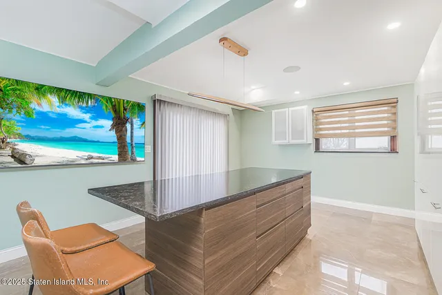 a kitchen with kitchen island granite countertop a sink and a refrigerator
