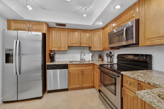 a bathroom with a granite countertop sink a toilet a mirror a shower and vanity