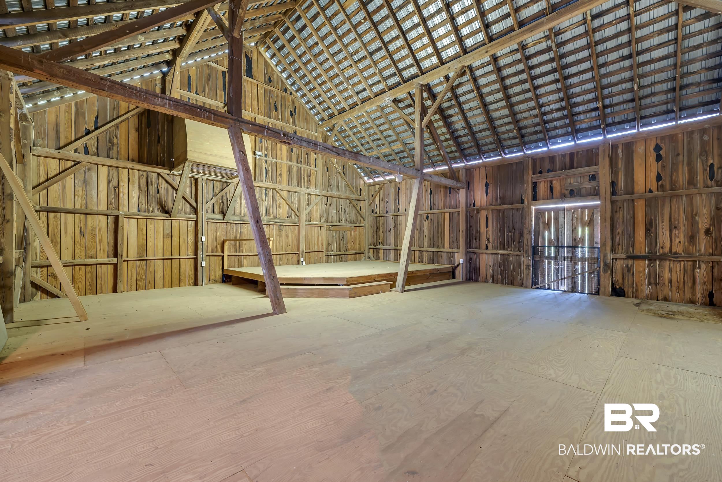 43199 Pine Grove Road Bay Minette, AL 36507 - Photo 24 of 71 Open barn interior featuring wood-paneled walls, exposed wood beam construction, a corrugated metal roof, and a raised wood platform