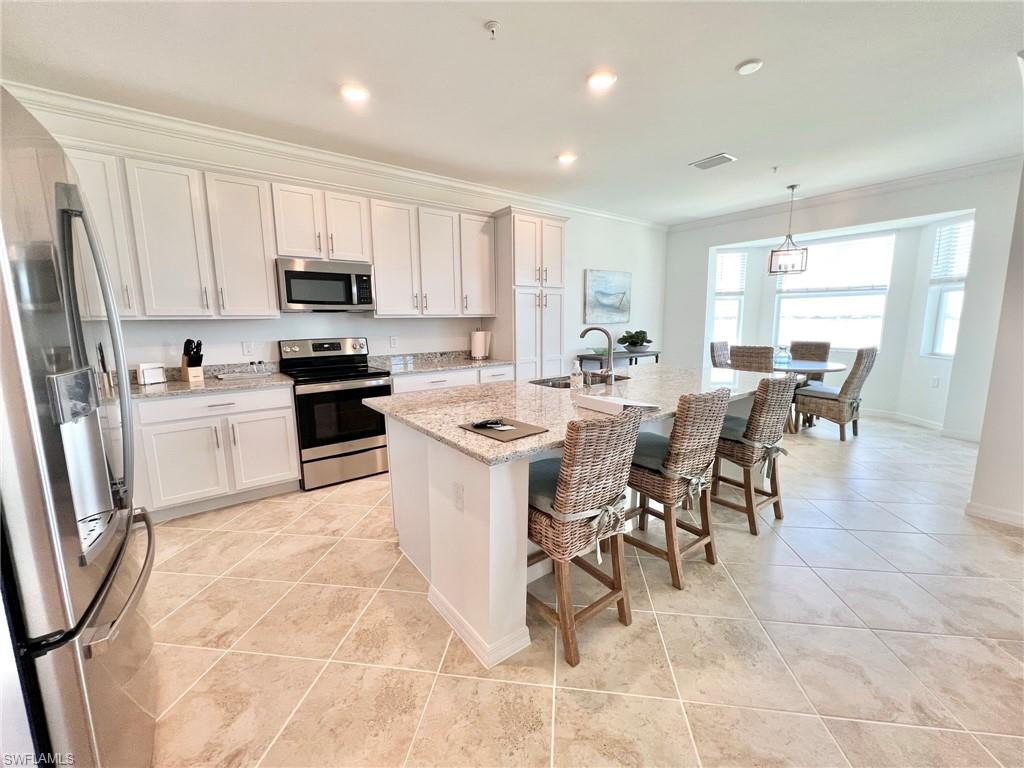 43020 Greenway Boulevard, Unit 345 Babcock Ranch, FL 33982 - Photo 3 of 42 a large kitchen with stainless steel appliances a stove a sink a dining table and chairs