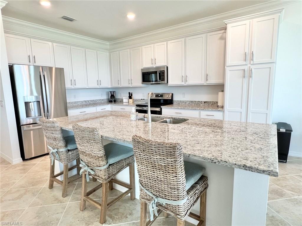 43020 Greenway Boulevard, Unit 345 Babcock Ranch, FL 33982 - Photo 4 of 42 a kitchen with stainless steel appliances granite countertop a stove a sink a microwave a refrigerator and white cabinets