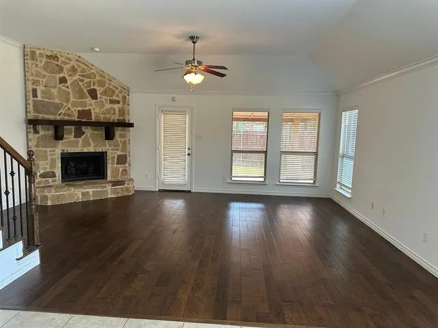 an empty room with windows fireplace and wooden floor