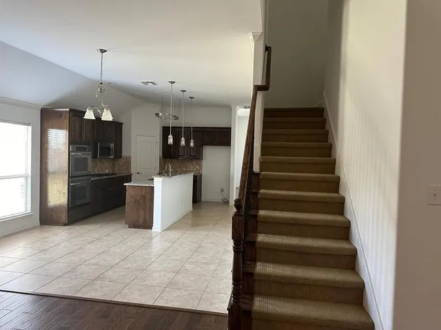 a kitchen with stainless steel appliances kitchen island granite countertop a refrigerator and a sink