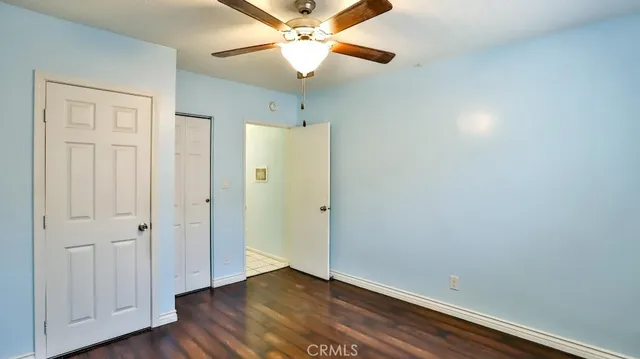 an empty room with wooden floor closet and ceiling fan