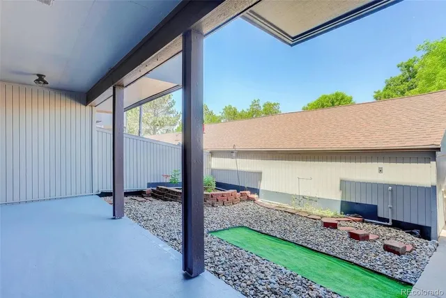 a view of backyard with wooden floor and iron fence