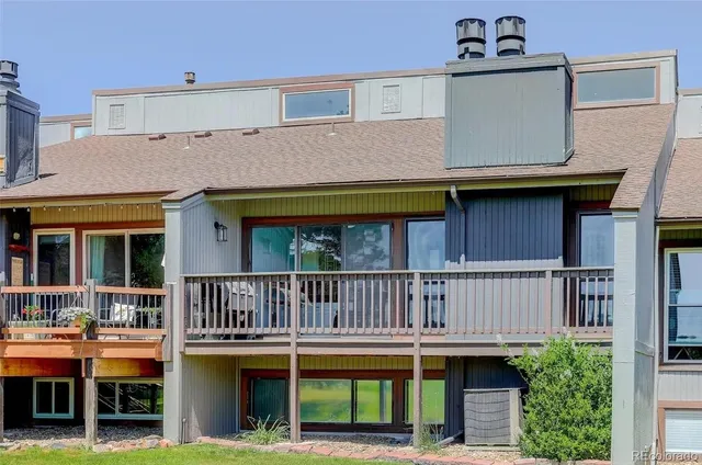 a view of small house with a wooden deck