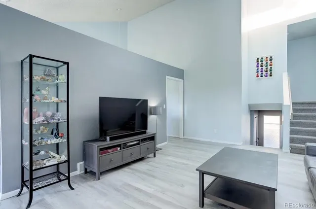 a kitchen with granite countertop a stove a sink and white cabinets with wooden floors