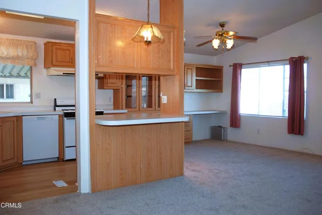 an empty room with chandelier fan and windows