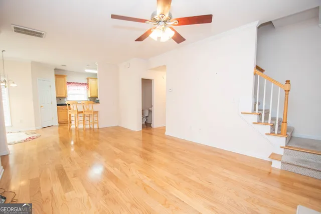 a view of a livingroom with wooden floor and a ceiling fan