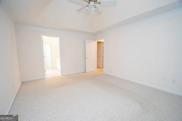 an empty room with a chandelier fan and windows