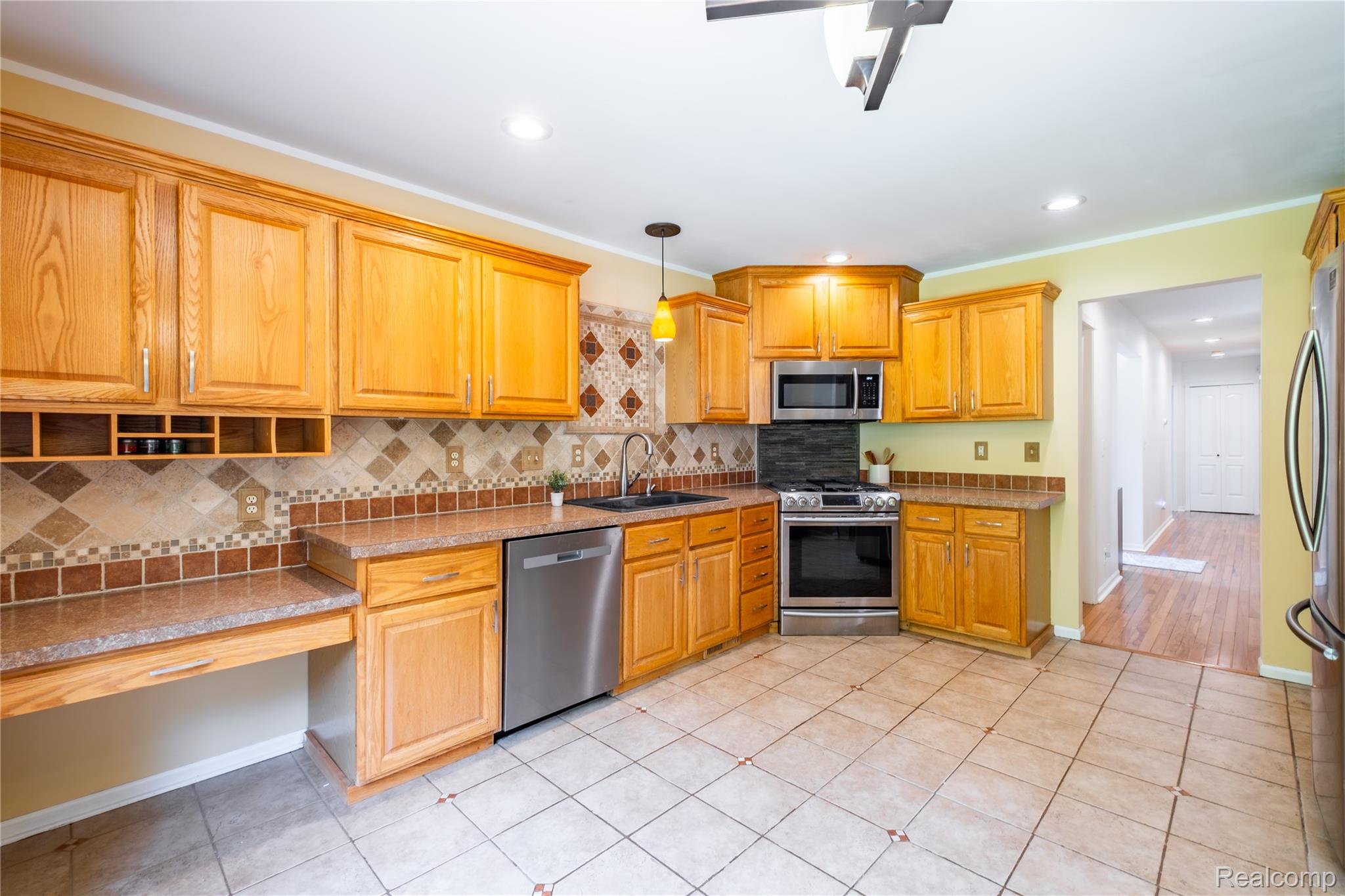 3483 Lahring Road Linden, MI 48451 - Photo 13 of 34 Kitchen featuring wood-finish cabinetry, stainless steel appliances, and a tile backsplash