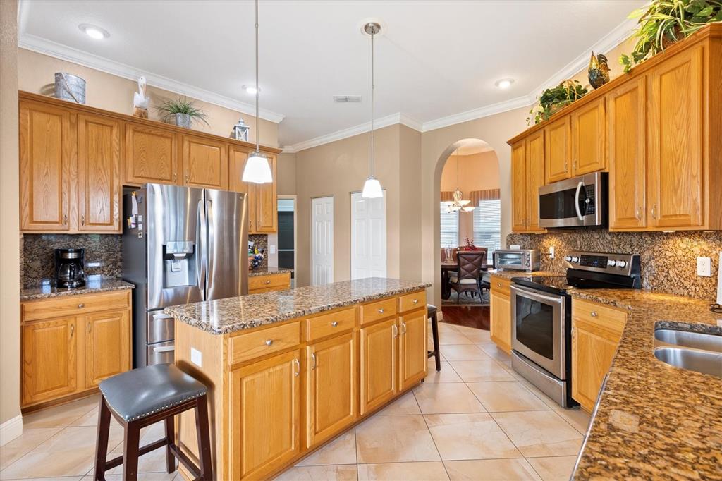 11839 Southeast 173rd Ln Road Summerfield, FL 34491 - Photo 15 of 49 a large kitchen with kitchen island granite countertop a stove top oven a sink dishwasher a dining table and chairs with wooden floor