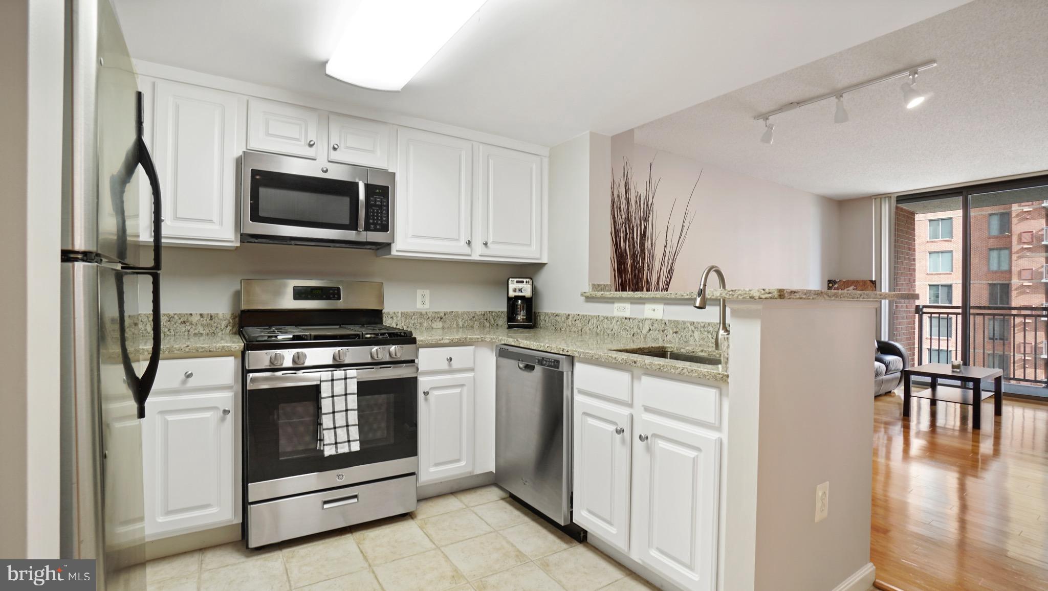 11710 Old Georgetown Road, Unit 1026 Rockville, MD 20852 - Photo 8 of 22 a kitchen with stainless steel appliances granite countertop a stove top oven a sink and white cabinets