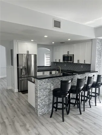 a kitchen with stainless steel appliances granite countertop a stove a sink a refrigerator and a microwave