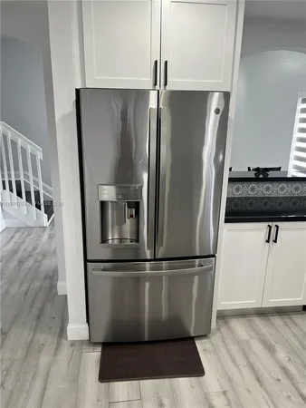 a view of a refrigerator in kitchen and an empty room