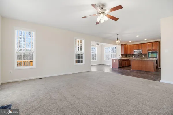 a kitchen with stainless steel appliances granite countertop wooden cabinets a refrigerator a sink a stove a microwave and island with wooden floor