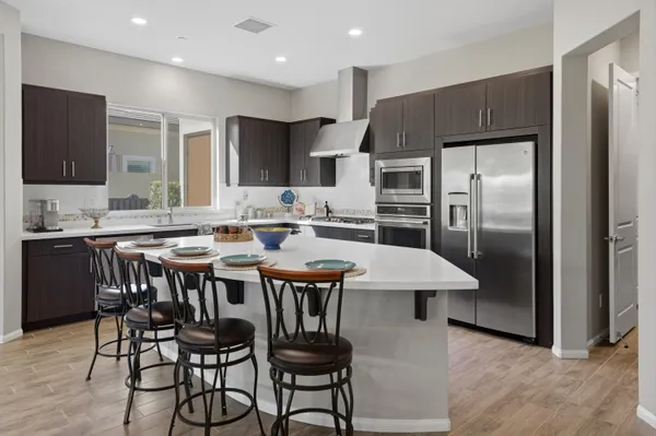 a kitchen with stainless steel appliances a dining table chairs sink and cabinets