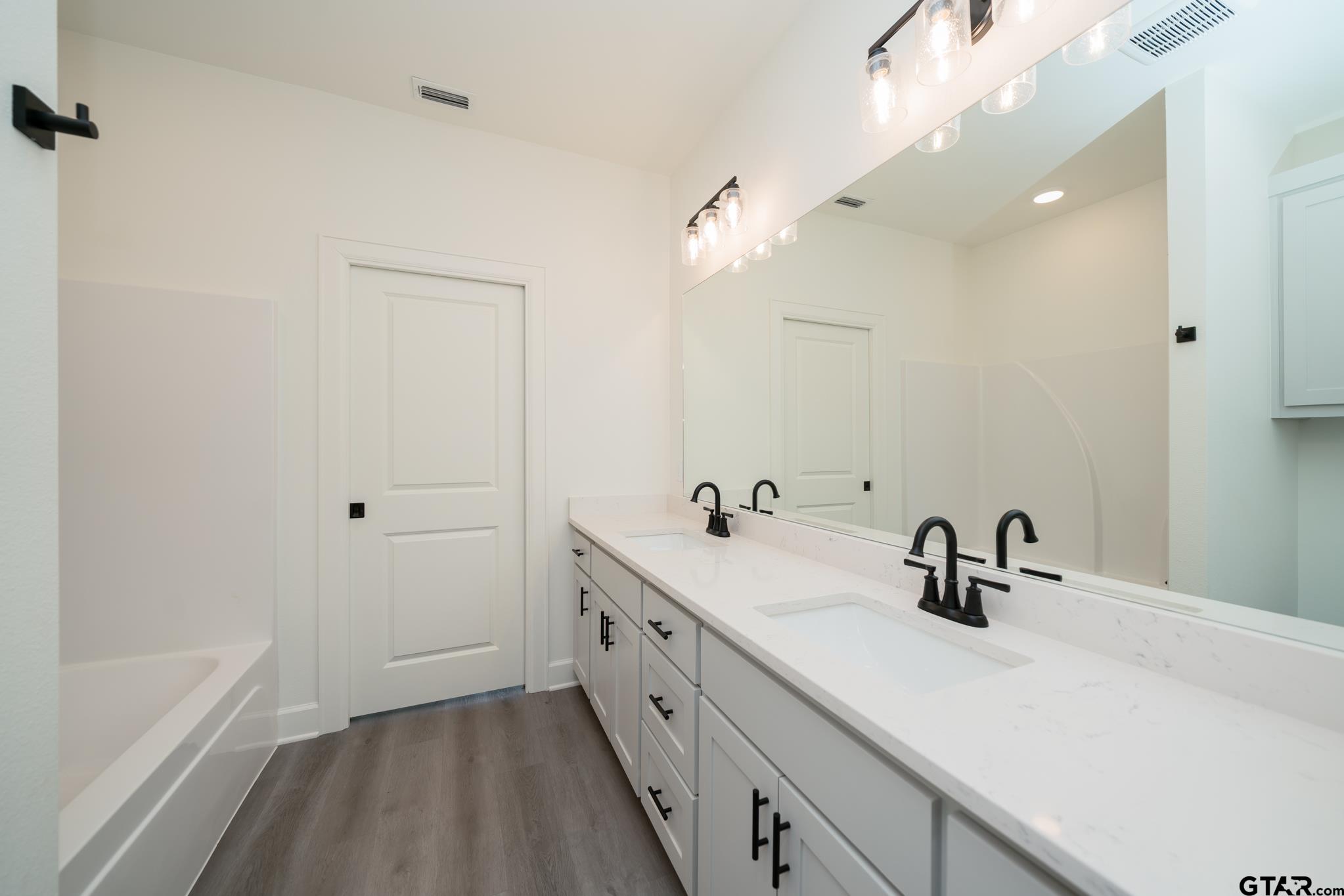 390 Alexander Street Kilgore, TX 75662 - Photo 22 of 34 a bathroom with a double vanity sink mirror and bathtub