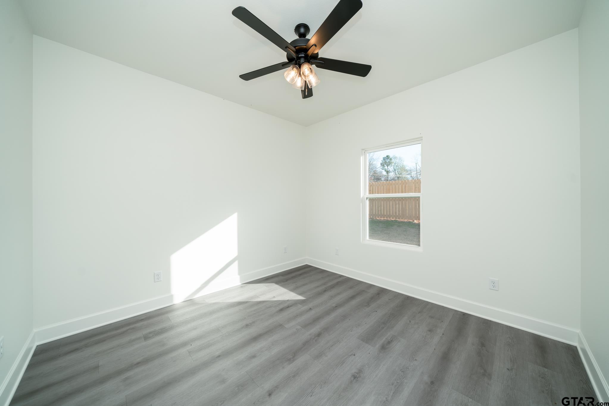 390 Alexander Street Kilgore, TX 75662 - Photo 25 of 34 an empty room with wooden floor and ceiling fan