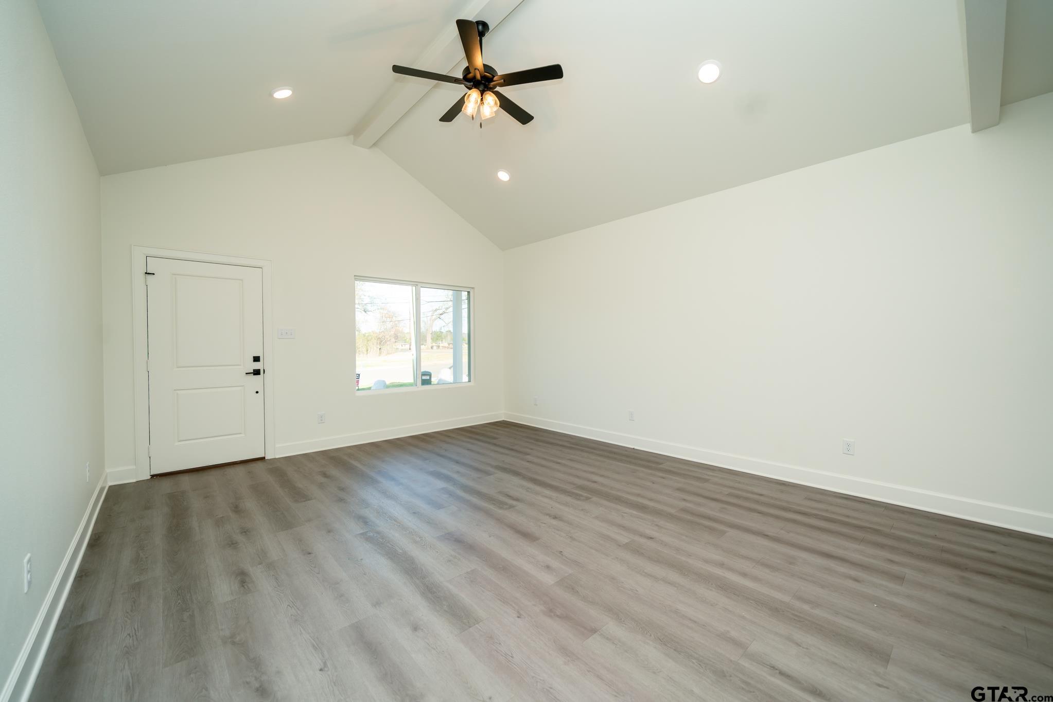 390 Alexander Street Kilgore, TX 75662 - Photo 8 of 34 an empty room with wooden floor ceiling fan and windows