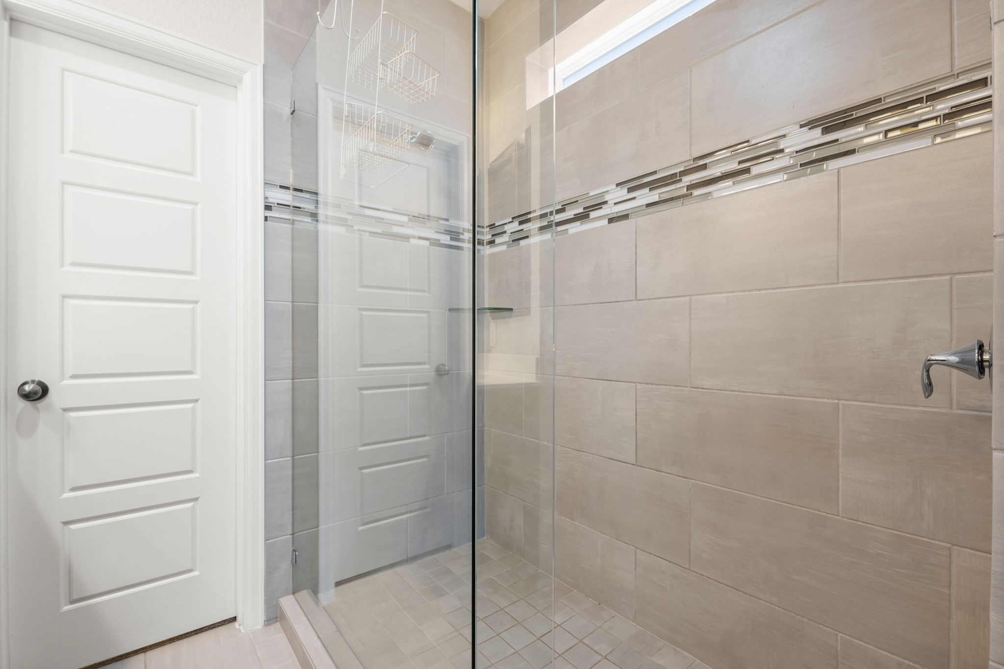 4403 Swift Path Austin, TX 78741 - Photo 15 of 32 Walk-in shower featuring glass enclosure, large format wall tiles, decorative accent tile band, and polished chrome fixtures