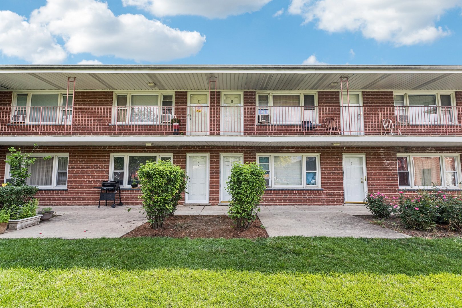 1115 East Algonquin Road, Unit 8 Arlington Heights, IL 60005 - Photo 1 of 11 a front view of a residential apartment building with a yard and potted plants
