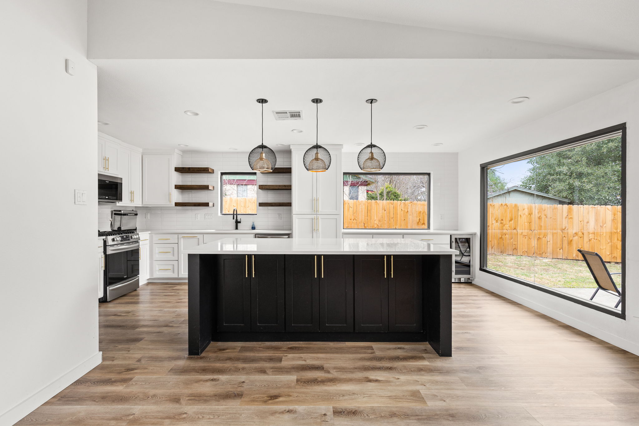 Dual tone kitchen with open shelves, decorative light fixtures, light wood finished floors, stainless steel appliances, and two tone color scheme