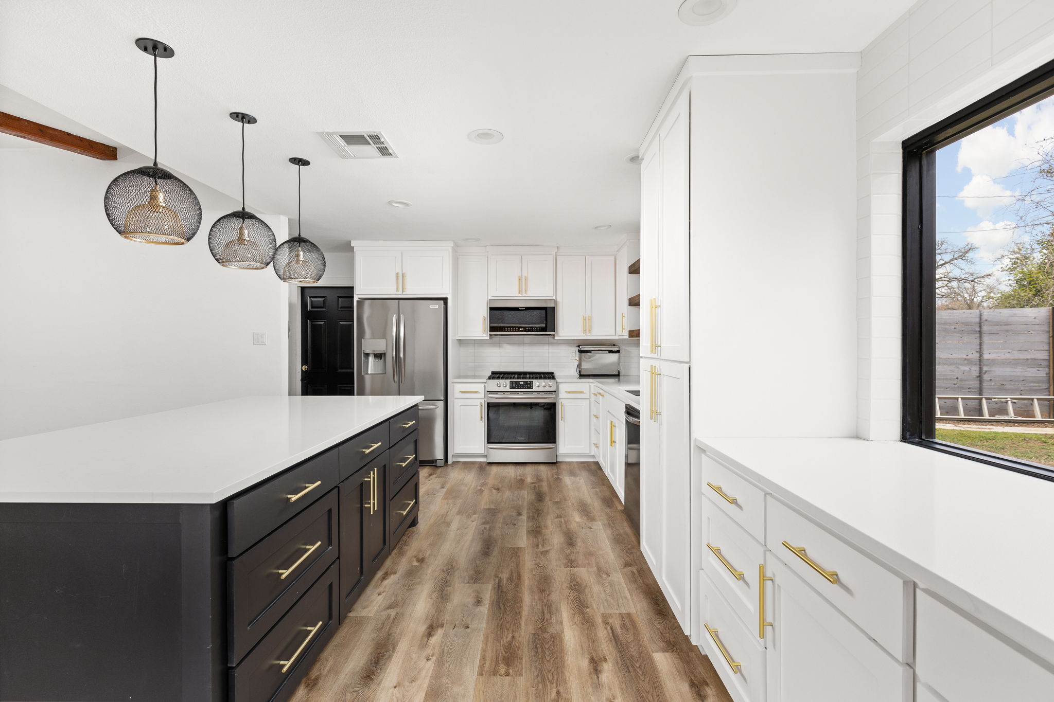 612 Meadowbrook Drive Georgetown, TX 78628 - Photo 13 of 35 Two tone kitchen featuring stainless steel appliances, light wood-style flooring, hanging light fixtures, dual tone cabinetry, and a center island
