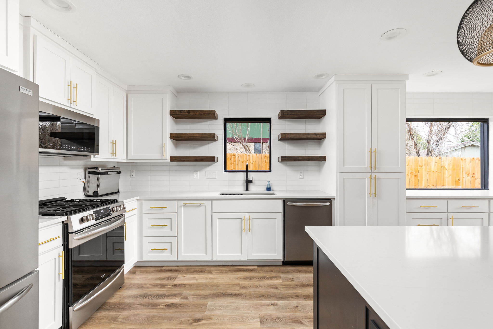 612 Meadowbrook Drive Georgetown, TX 78628 - Photo 15 of 35 Kitchen with stainless steel appliances, open shelves, light wood finished floors, two tone cabinets, and light stone counters
