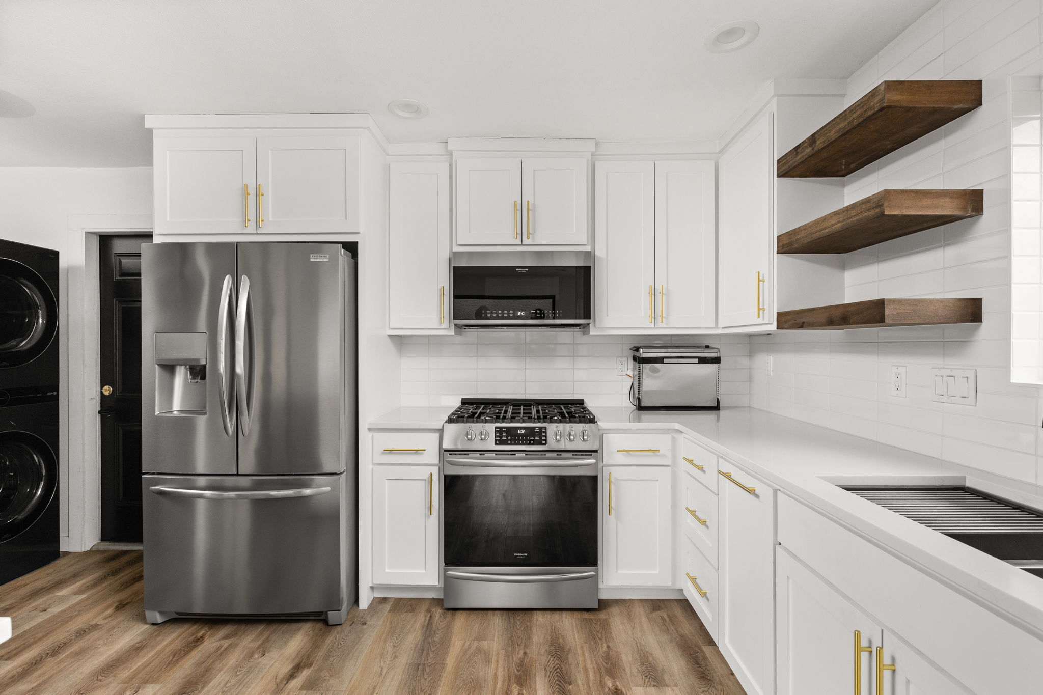 612 Meadowbrook Drive Georgetown, TX 78628 - Photo 16 of 35 Kitchen with stainless steel appliances, white cabinets, open shelves, and light wood finished floors