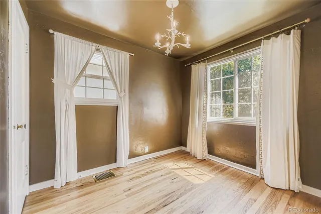 an empty room with wooden floor cabinet and windows