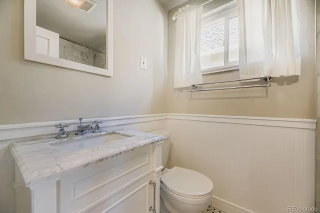 a bathroom with a granite countertop sink toilet and a mirror